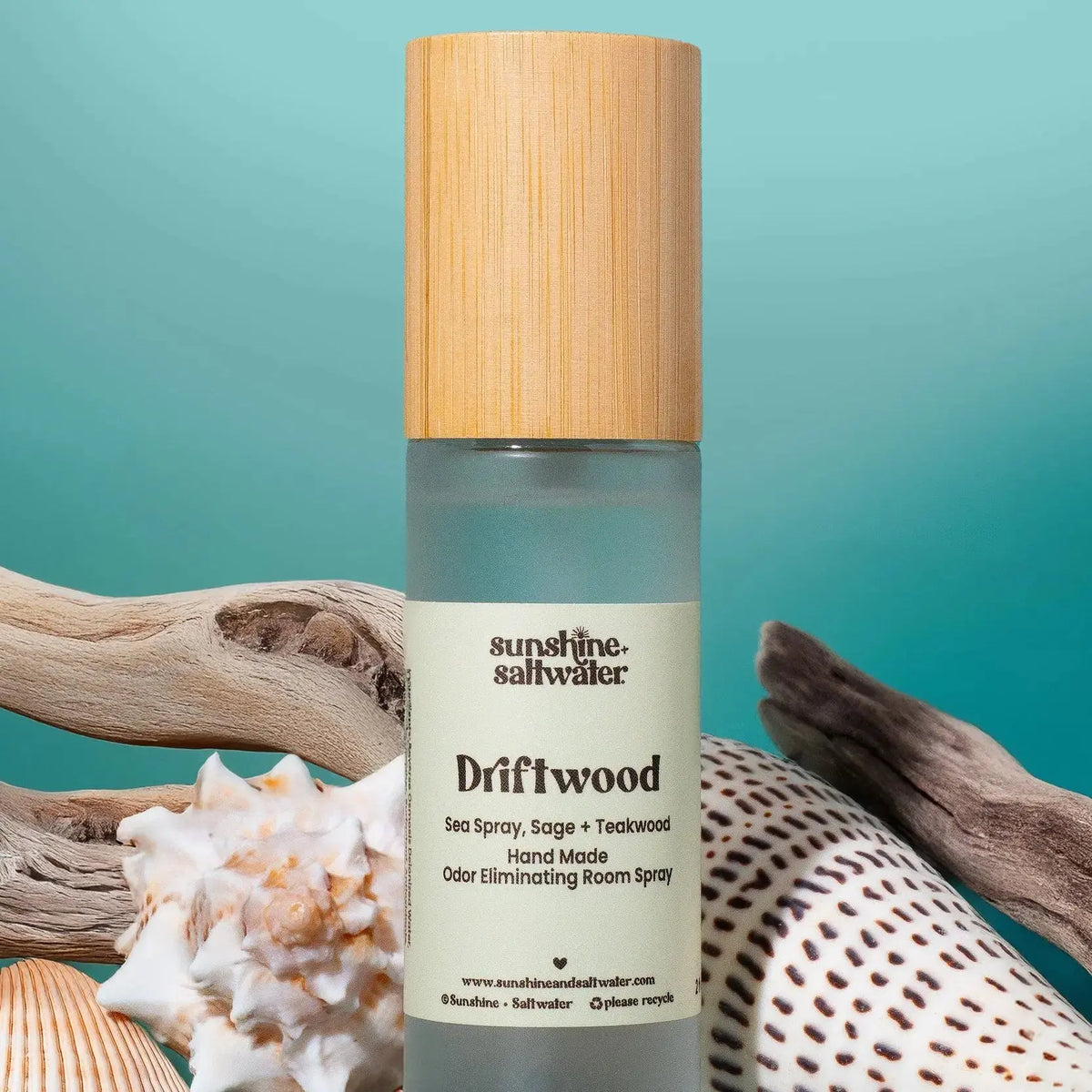 Room spray bottle labeled 'Driftwood' with natural elements on a teal background