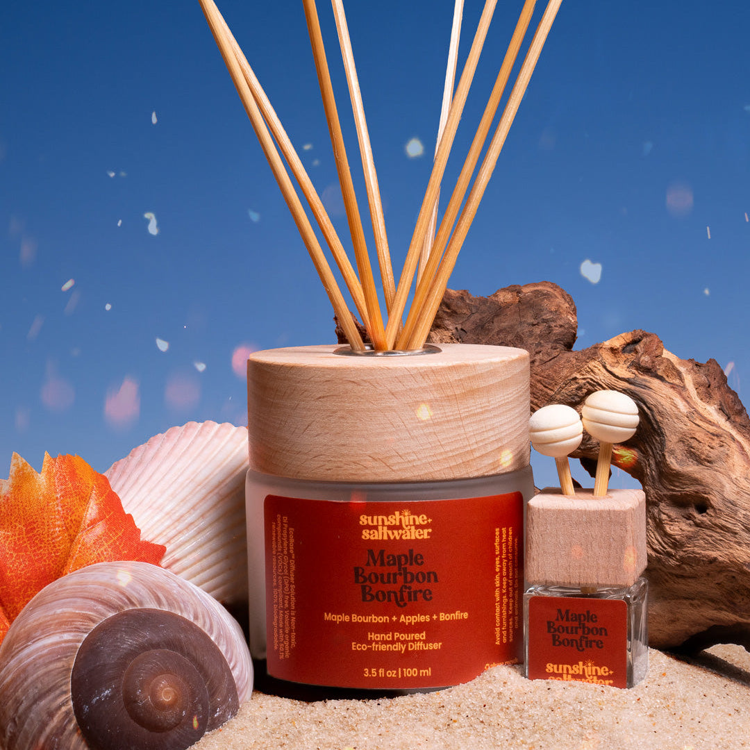 Scented diffuser set with wooden sticks, container, and small bottle on a beach-themed background.