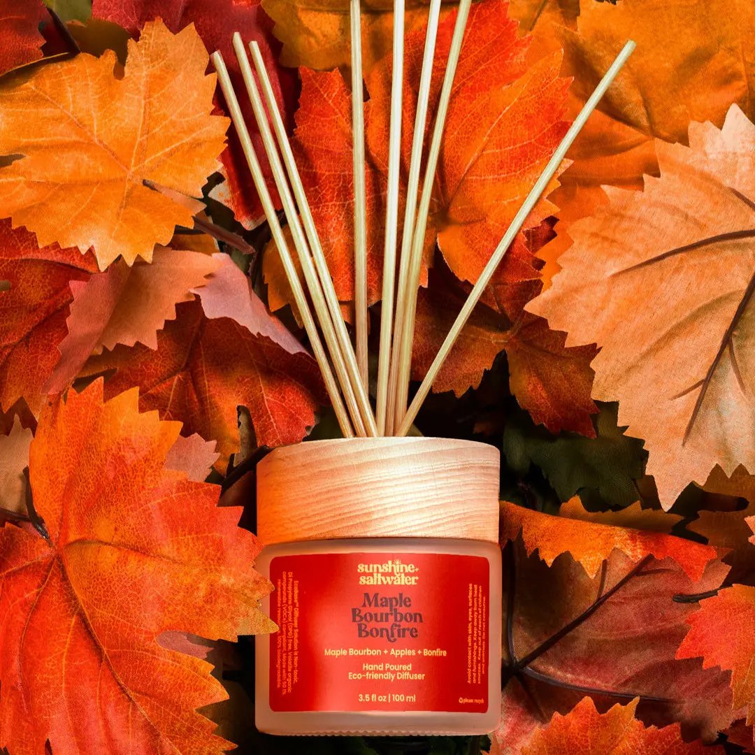 Reed diffuser with a red label on a bed of autumn leaves
