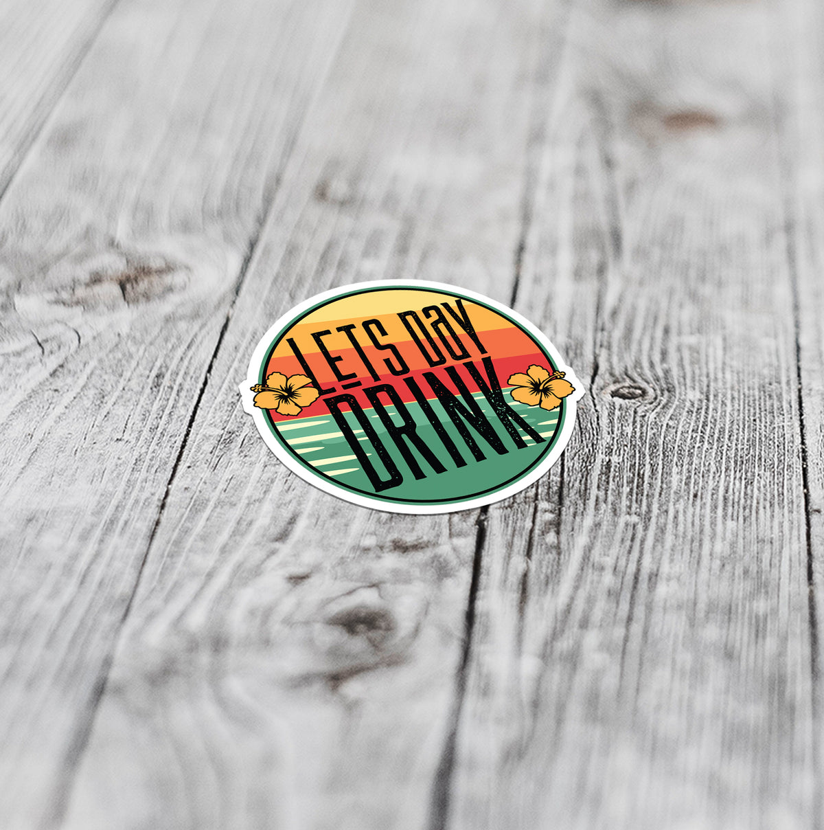 Flat lay of lets day drink sticker with sunset over the ocean