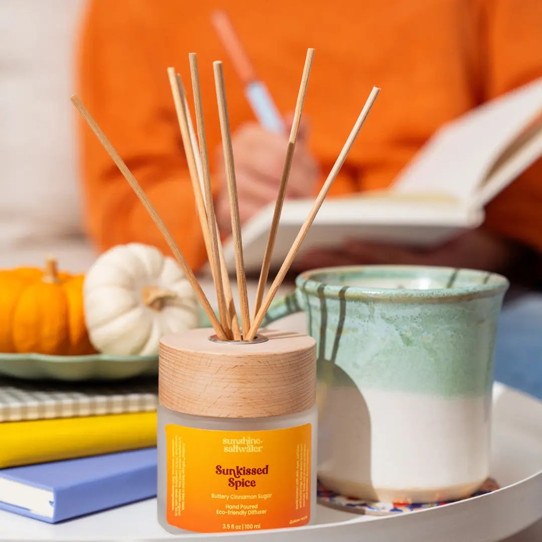 Diffuser with 'Sunkissed Spice' label surrounded by pumpkins and cinnamon sticks