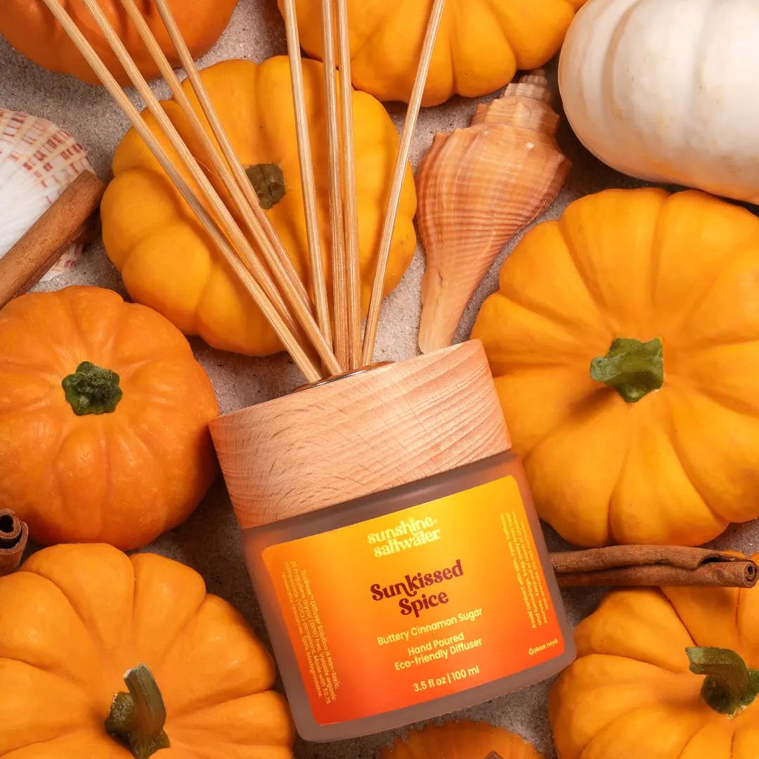 Diffuser with 'Sunkissed Spice' label surrounded by pumpkins and cinnamon sticks