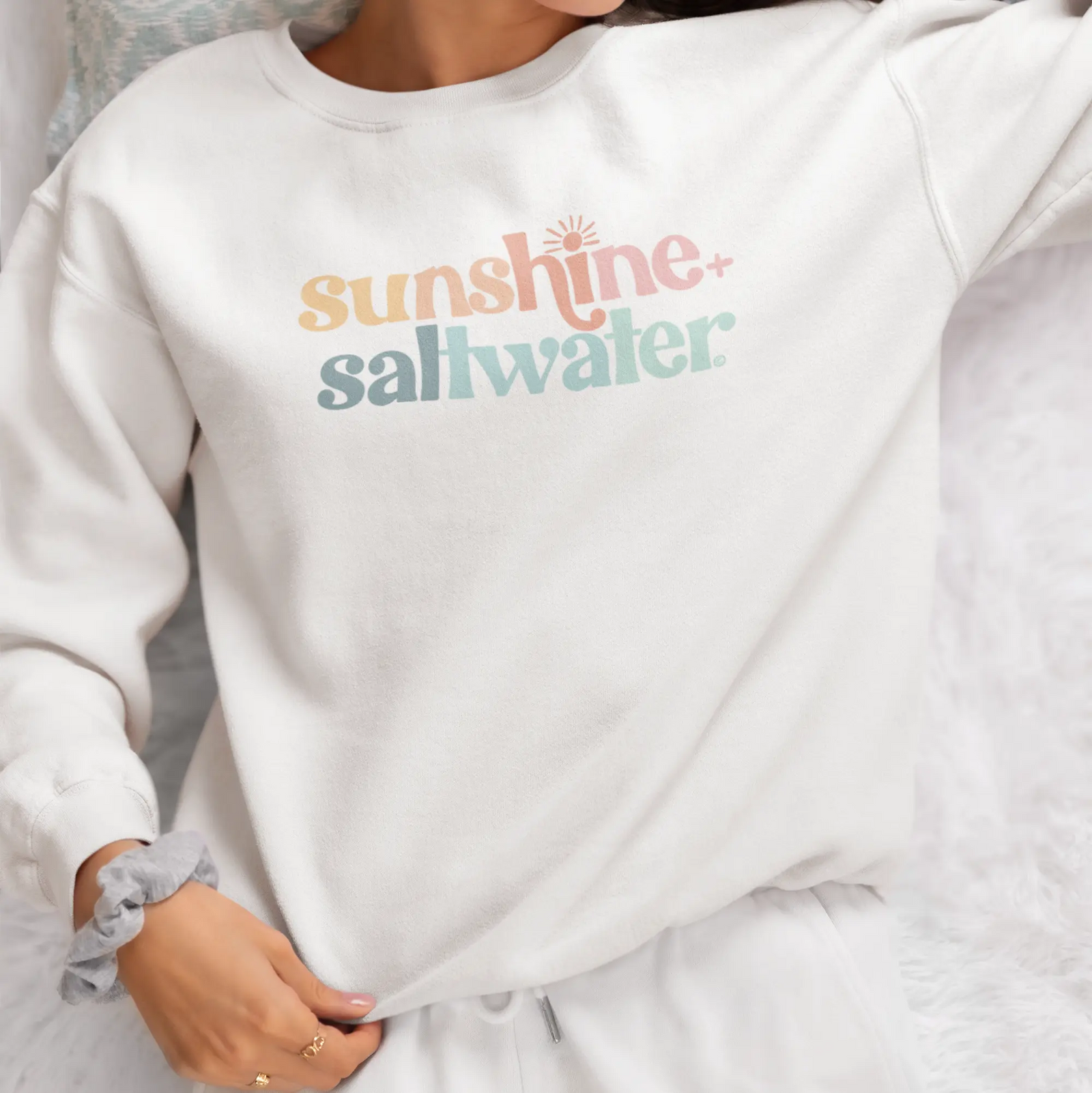 model wearing white crewneck beach sweatshirt with sunshine and saltwater printed in colorful print
